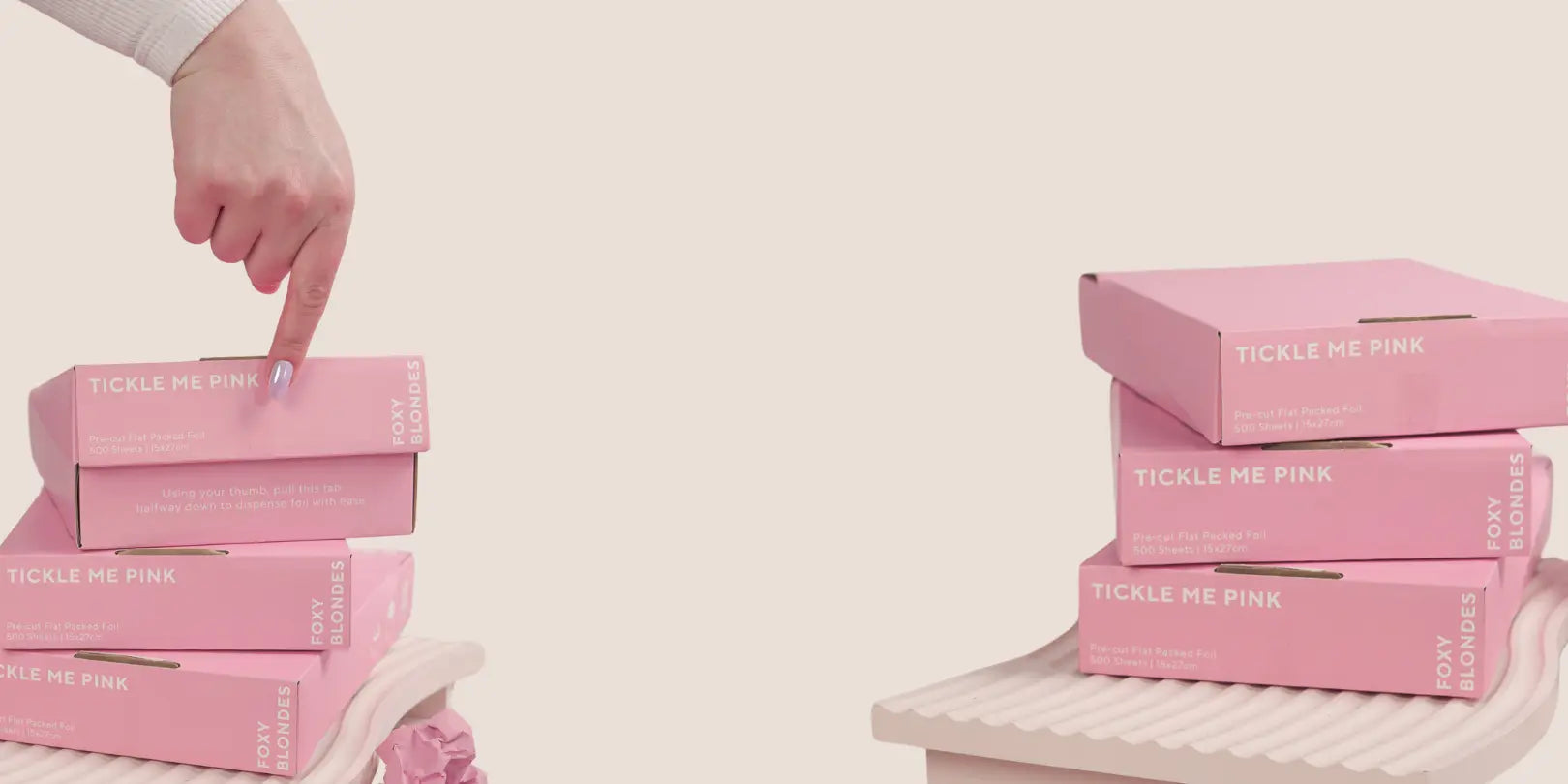 Two stacks of Foxy Blondes 'Tickle Me Pink' pre-cut flat-pack hair foil boxes (500 sheets, 15x27cm),  displayed on pink ridged stands with crumpled foils.